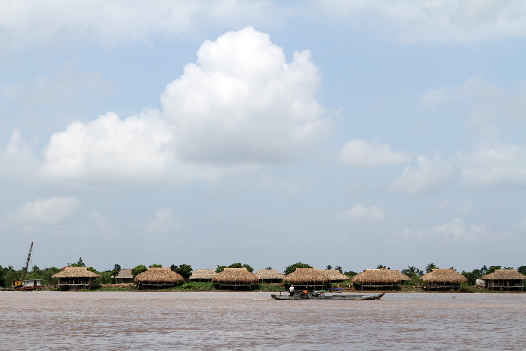 Thatched Homes border the Mekong river in Vietnam.